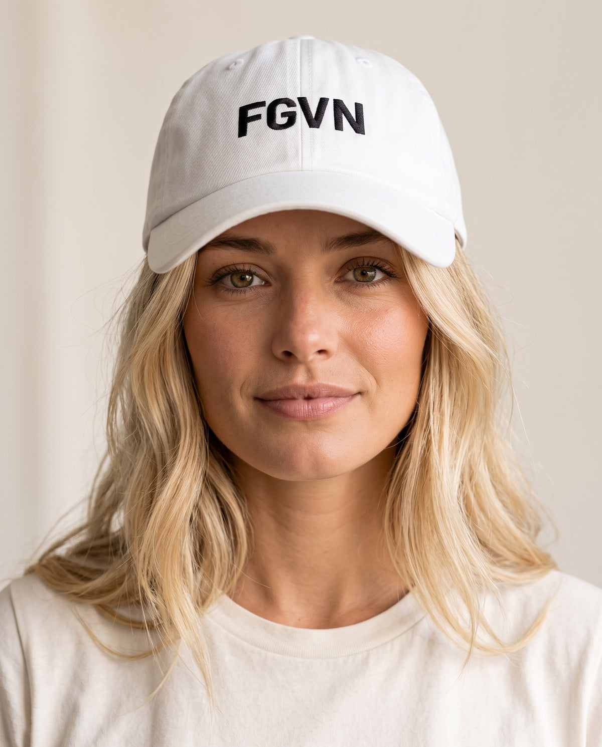 Taylor wears a white twill cap in a front-facing photograph.
